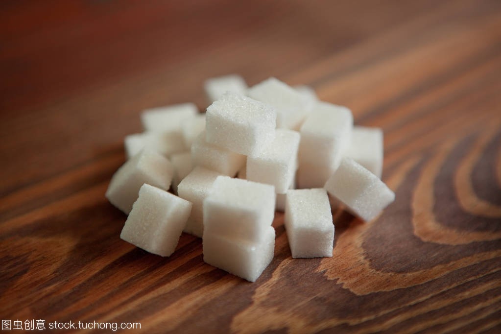 棕色木桌上的白糖立方體